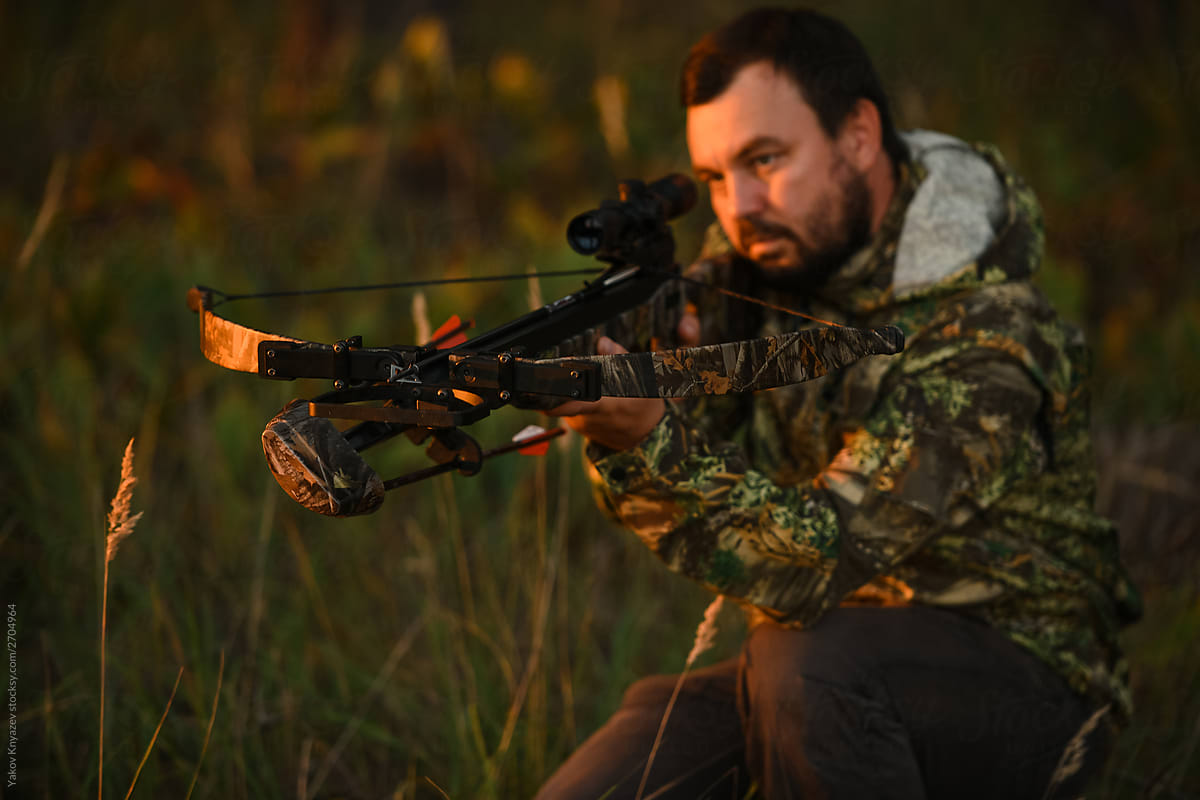 Adult man hunting with a recurved crossbow in the forest on an autumn day.