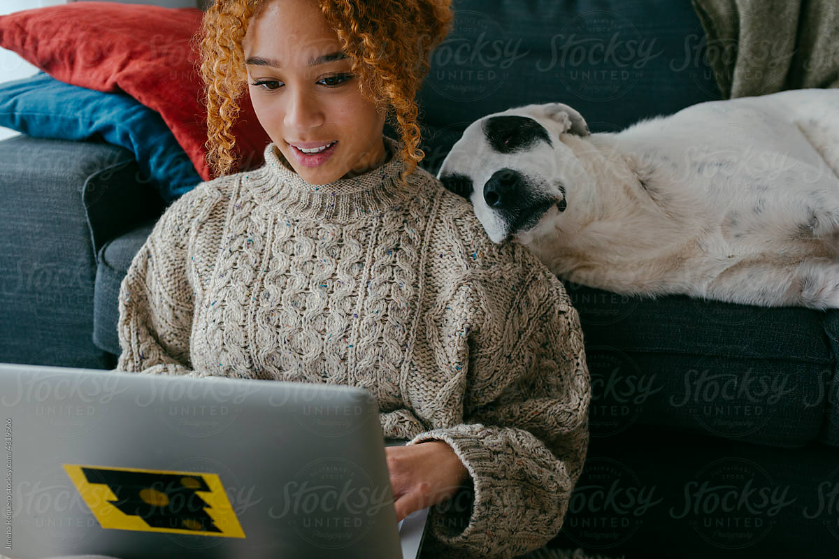 Teenager using laptop at home while dog sleeps