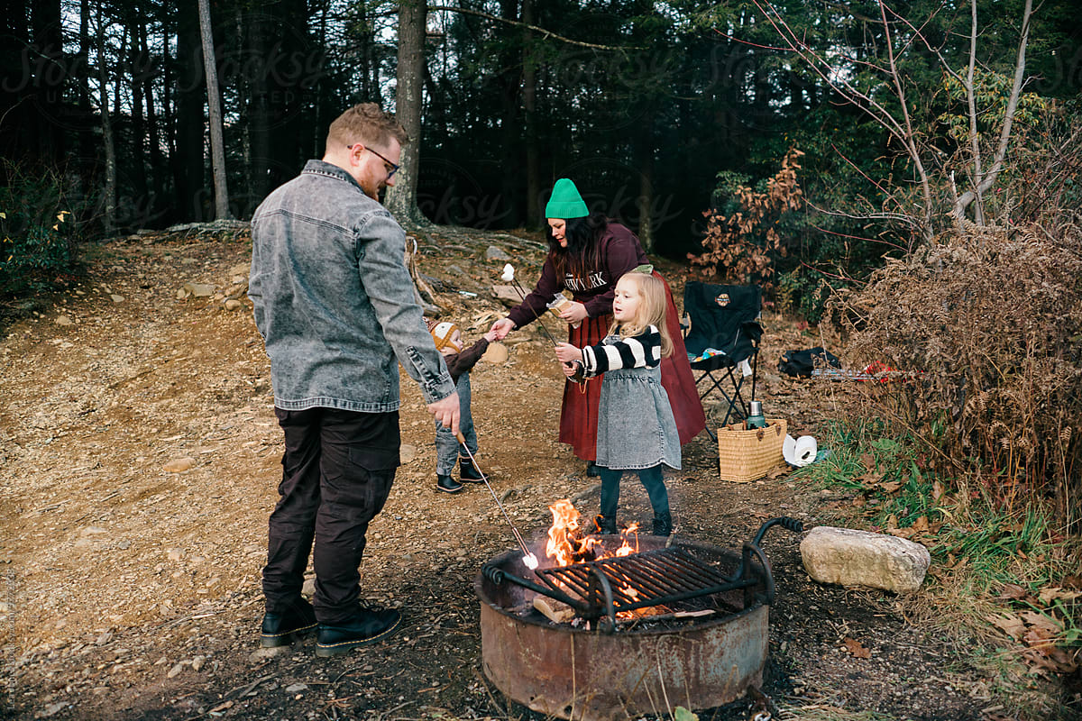 family making smores  by a camp fire by a lake