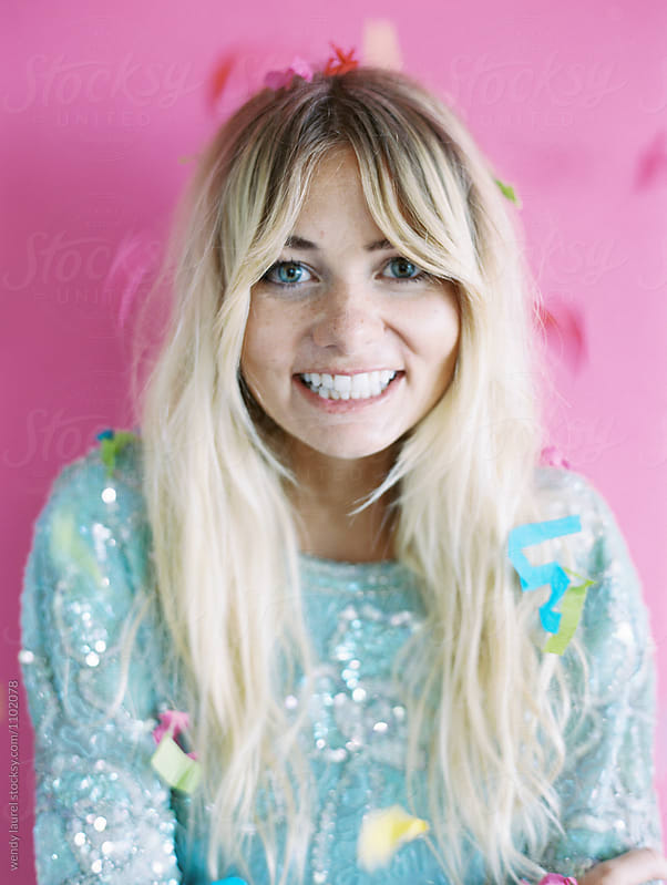 blonde in blue dress against pink wtih confetti