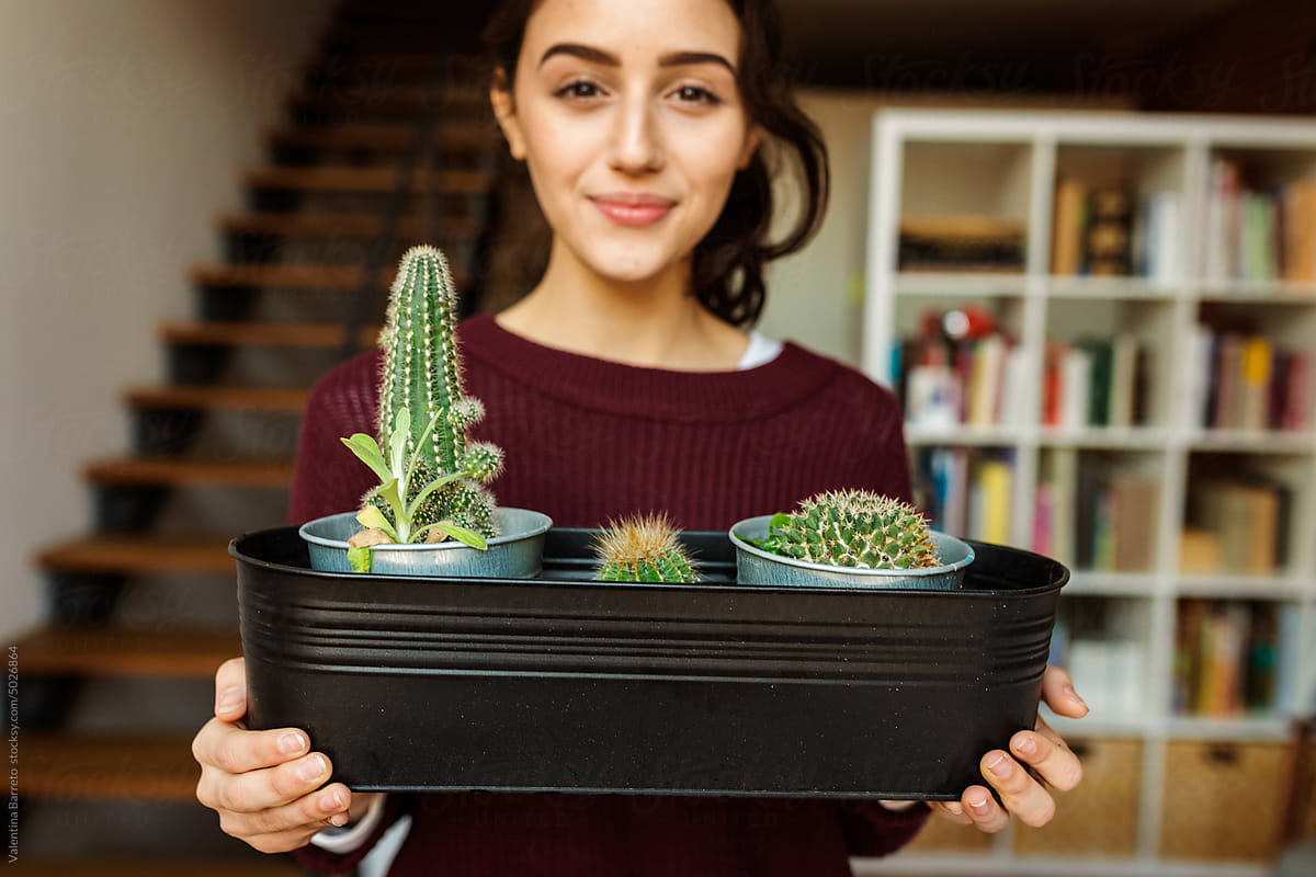 Young woman holding potted cactus at home