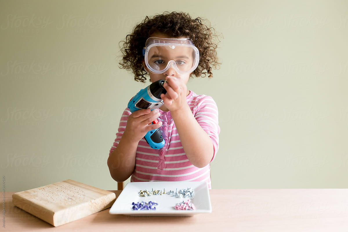 Girl in safety glasses with blue screwdriver