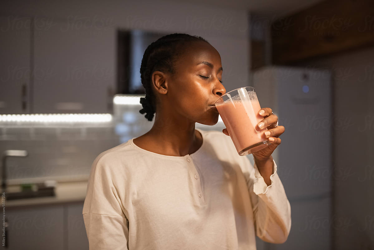 Black woman drinking strawberry smoothie at home