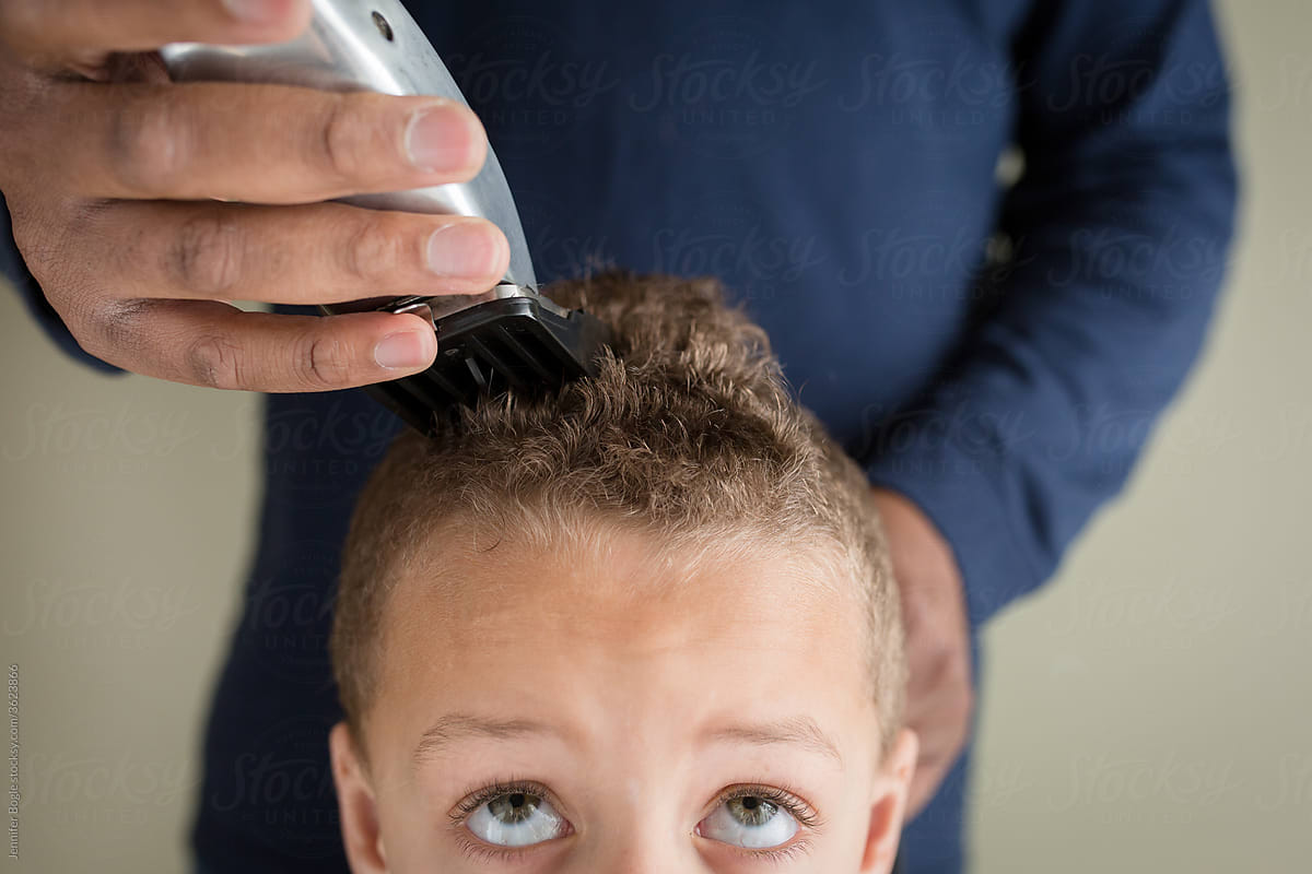 Boy looks up as father shaves his hair