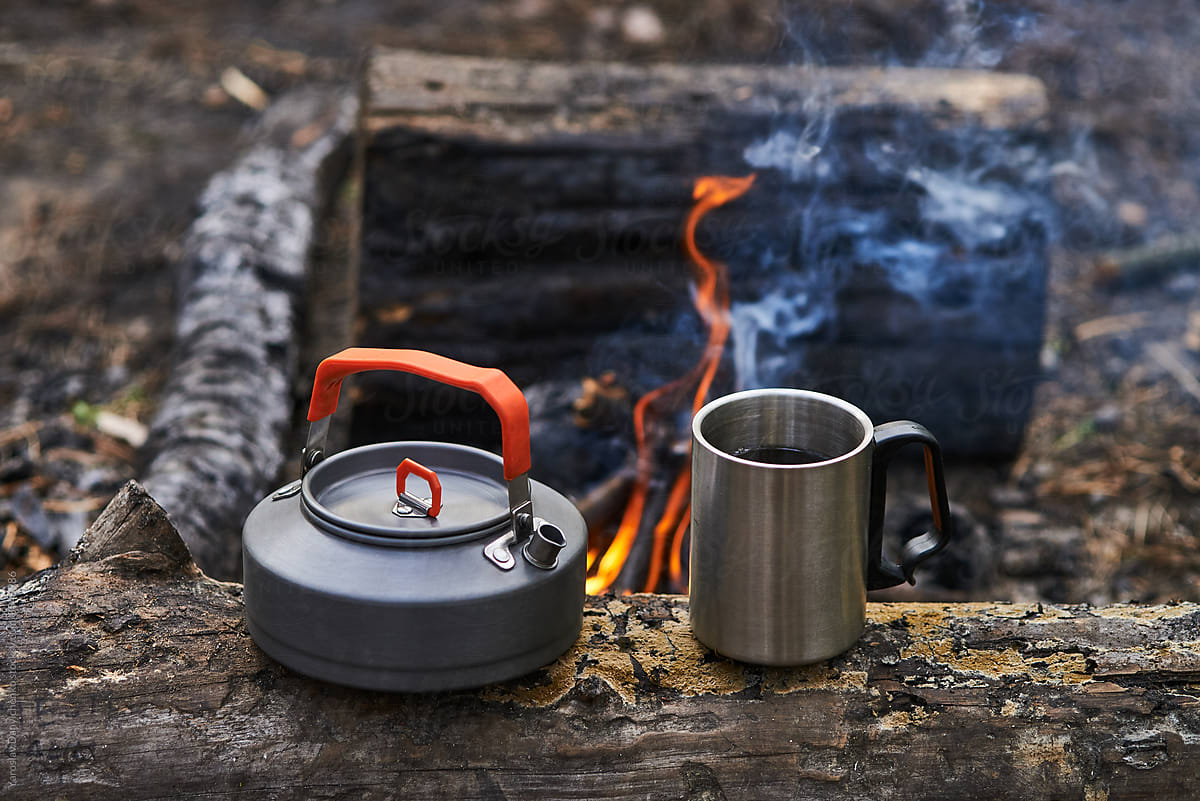 Titanium kettle and metal mug of freshly brewed tea.