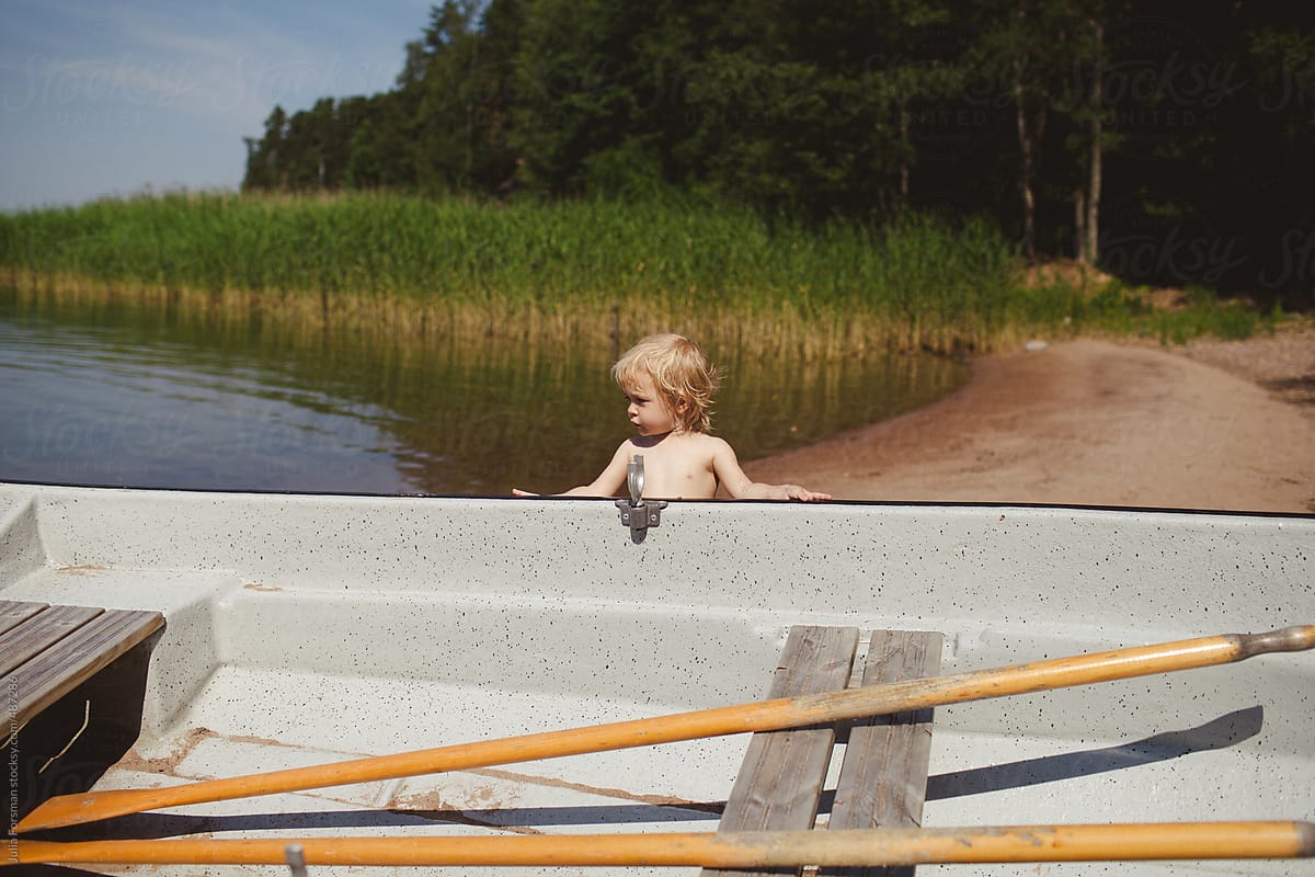 A small child tries to push a boat out into the Finnish Archipelago.