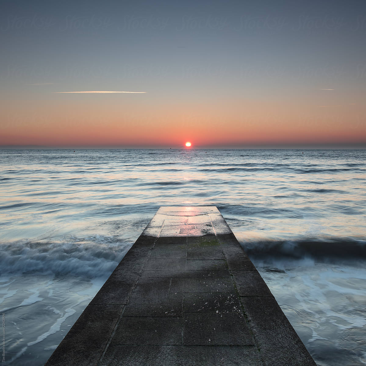 A jetty pointing towards the sunrise.