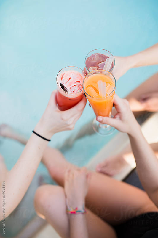 Friends drinking cocktails by the pool
