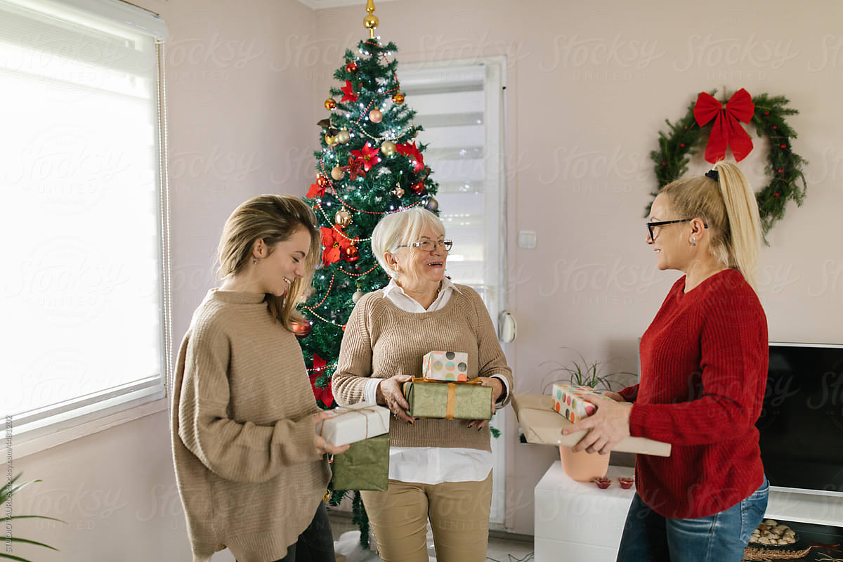 Cheerful women exchanging Christmas presents at home