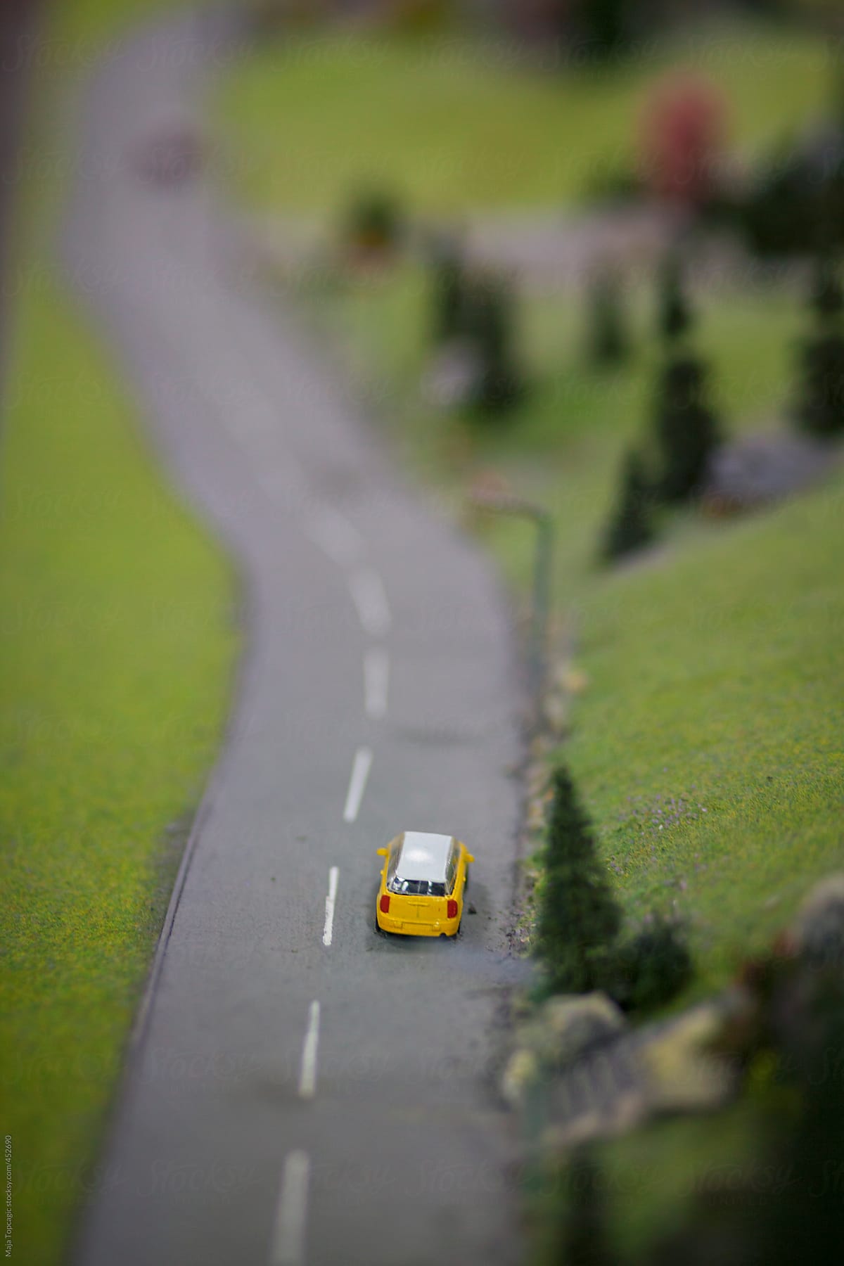 A yellow car on the road on a model of an eco village in a smaller scale