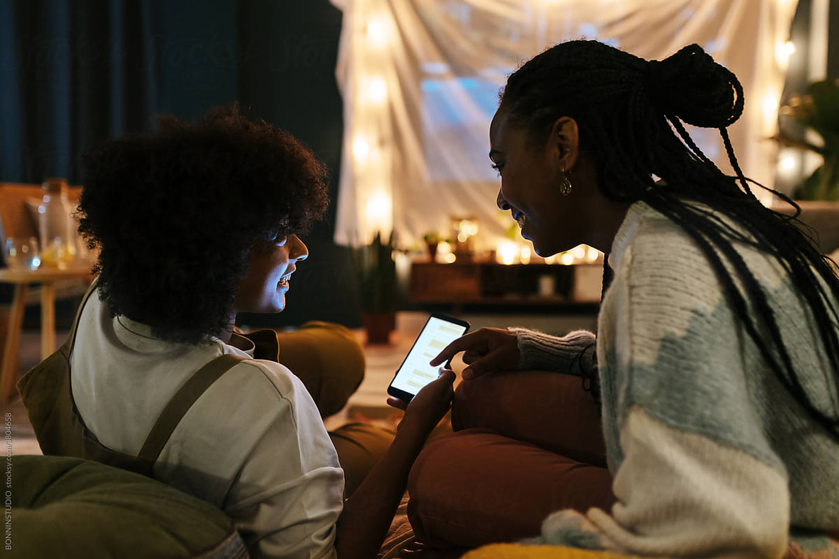Black girlfriends using smartphone together at movie night