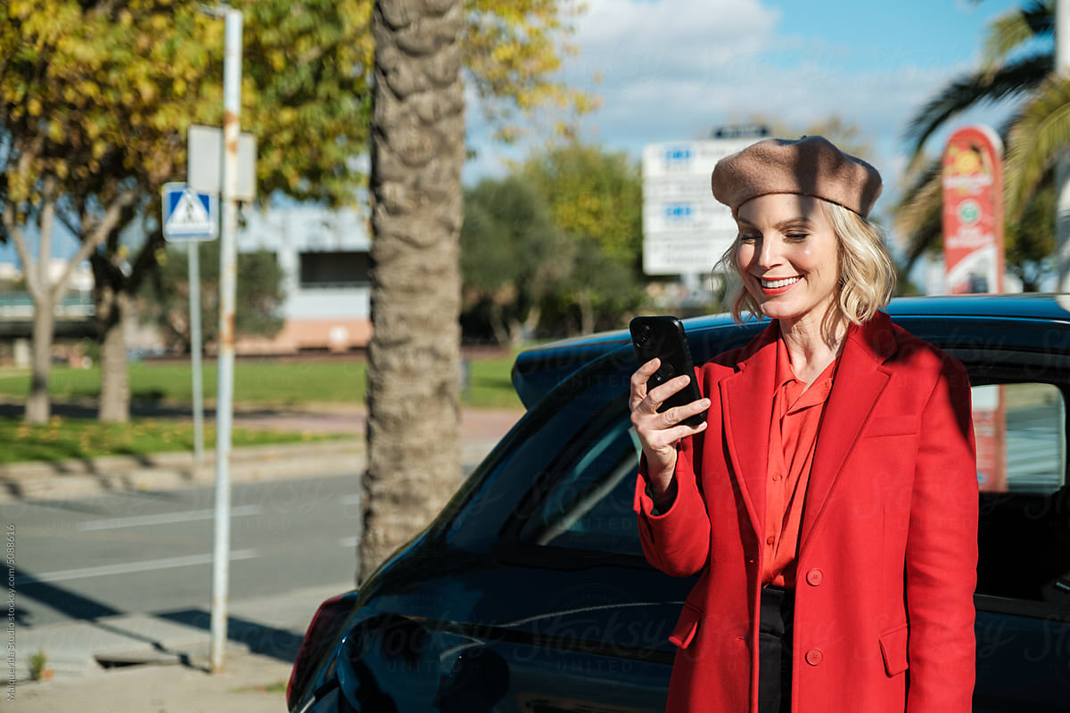 Woman browsing phone while recharging electric car
