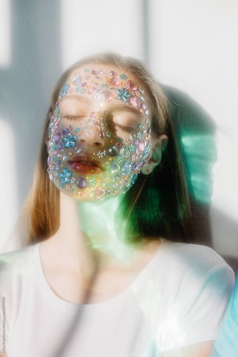 Soft focus portrait of teen girl with gems on face