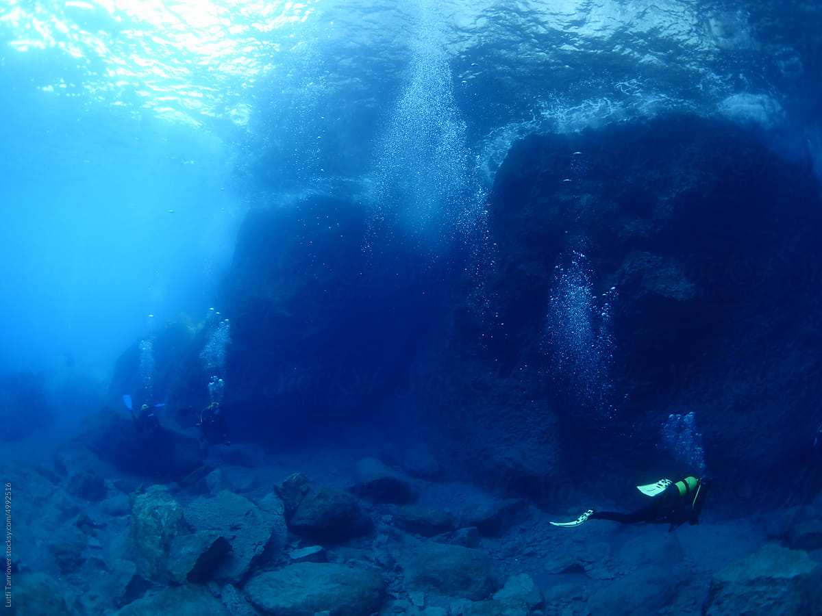 scuba divers exploring strange shape rocks and underwater topography