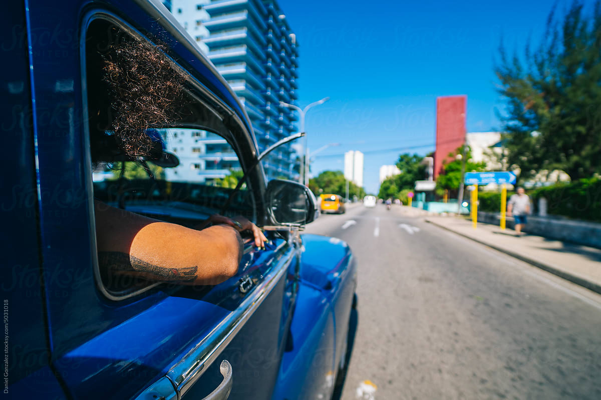 An unrecognizable woman travels in a car on the street of Havana