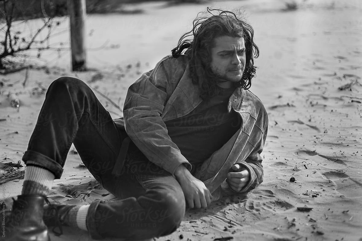 black and white portrait of a man traveler lying on the sand in clothes