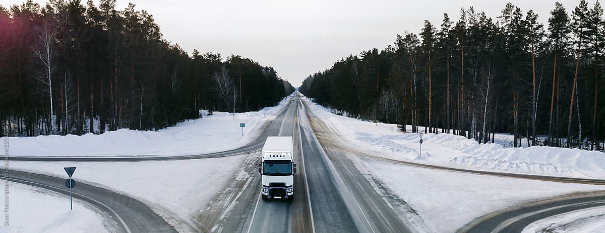 The truck rides on a winter snowy road in the forest.