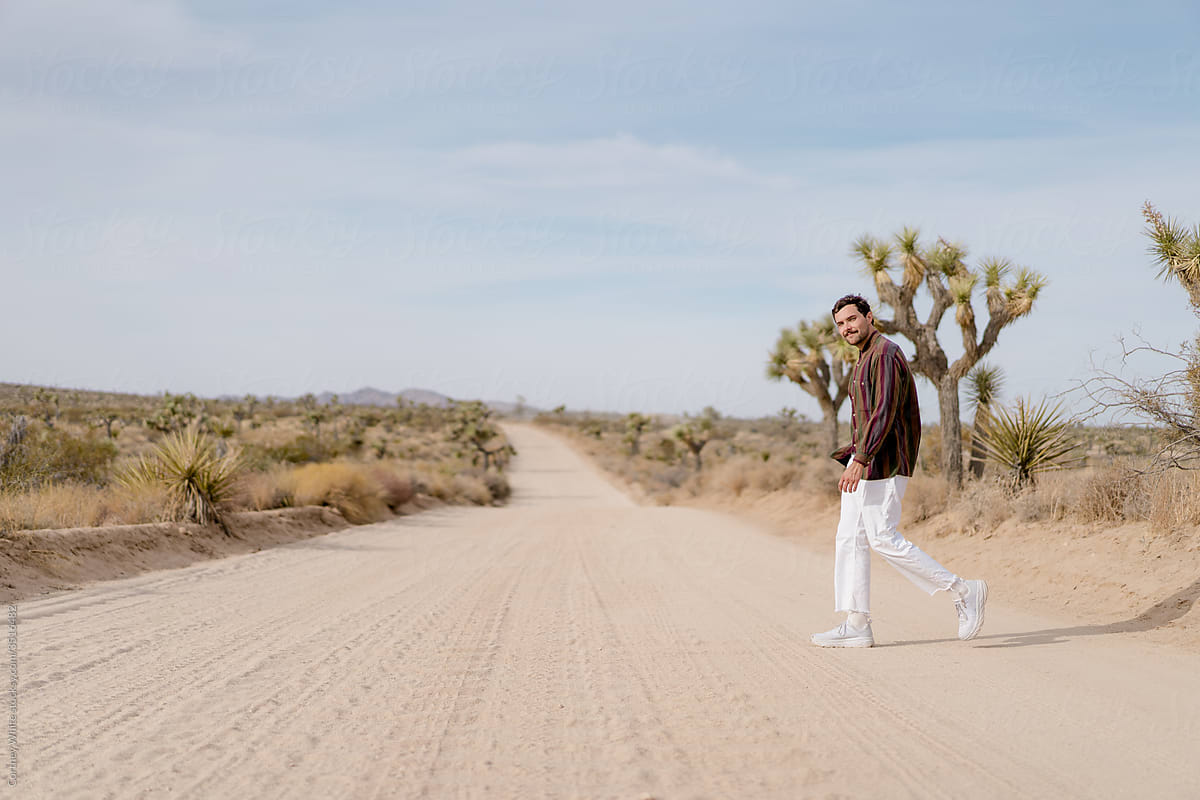 Man Walking Down Dirt Road In The Desert