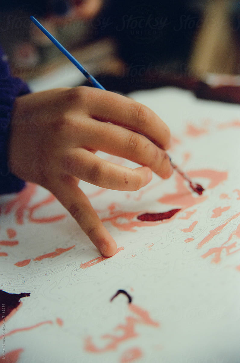 A Child\'s Hand Draws A Picture With Brush and Paints