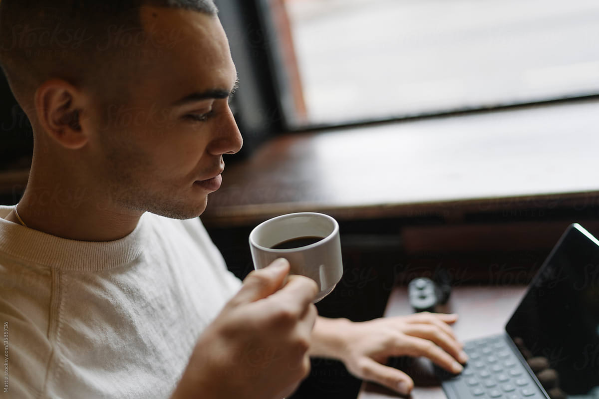 Man Drinking a Coffee and Working from a Coffee Shop