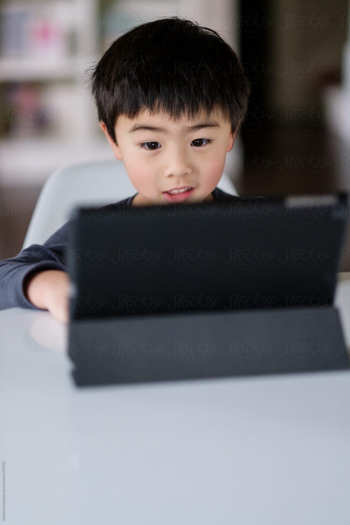 Asian boy playing game on a tablet PC