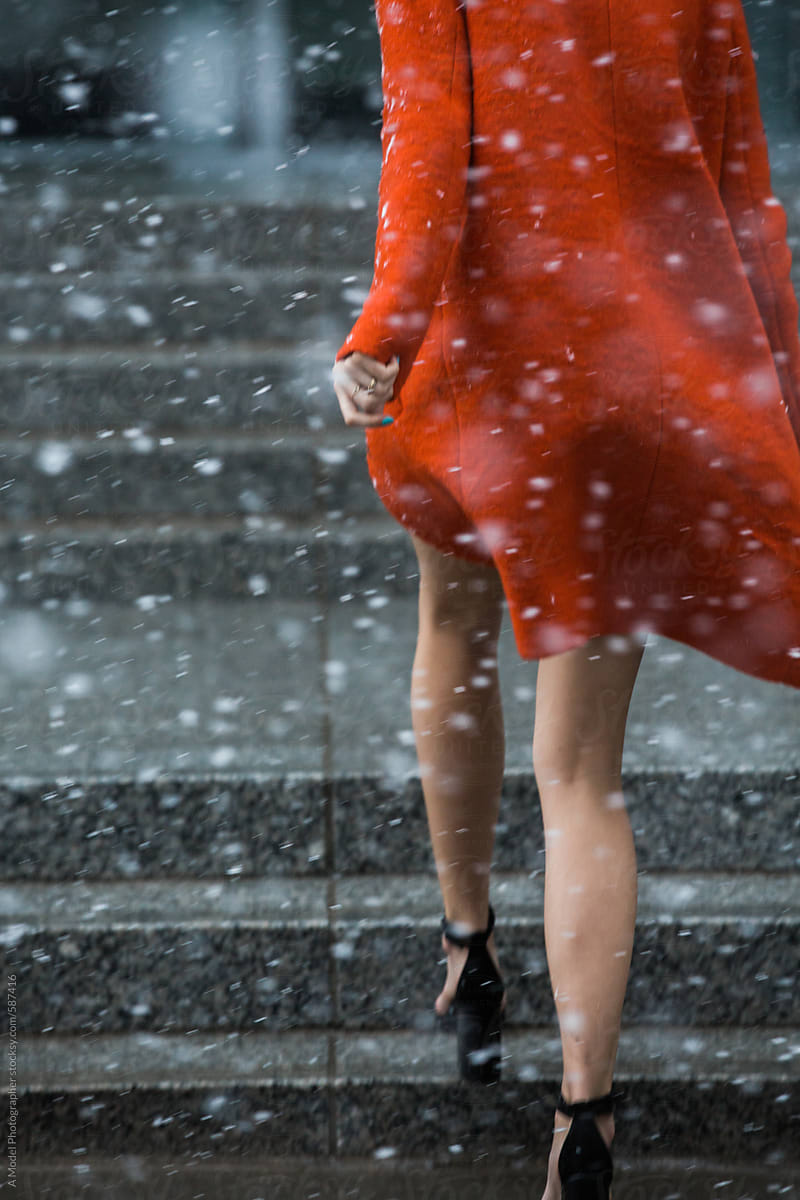 Legs and heels walking away in a colorful jacket, with falling snow