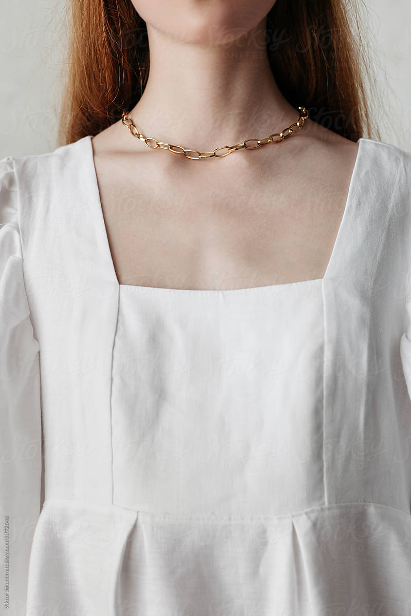 Crop of woman in white linen dress with golden chain on her neck