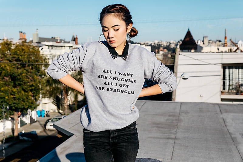 young woman on rooftop wearing ironic phrase on sweatshirt