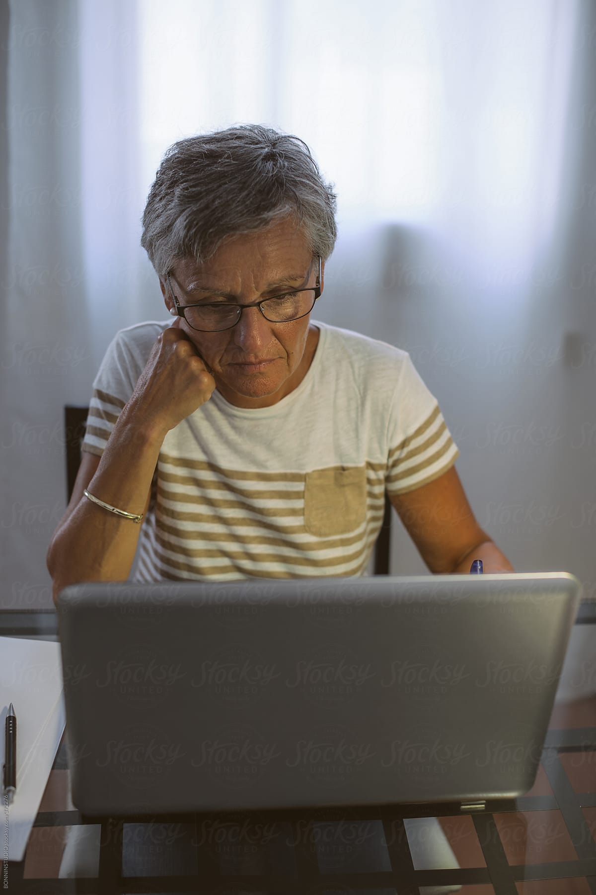 Mature woman reading a document on her laptop at home.