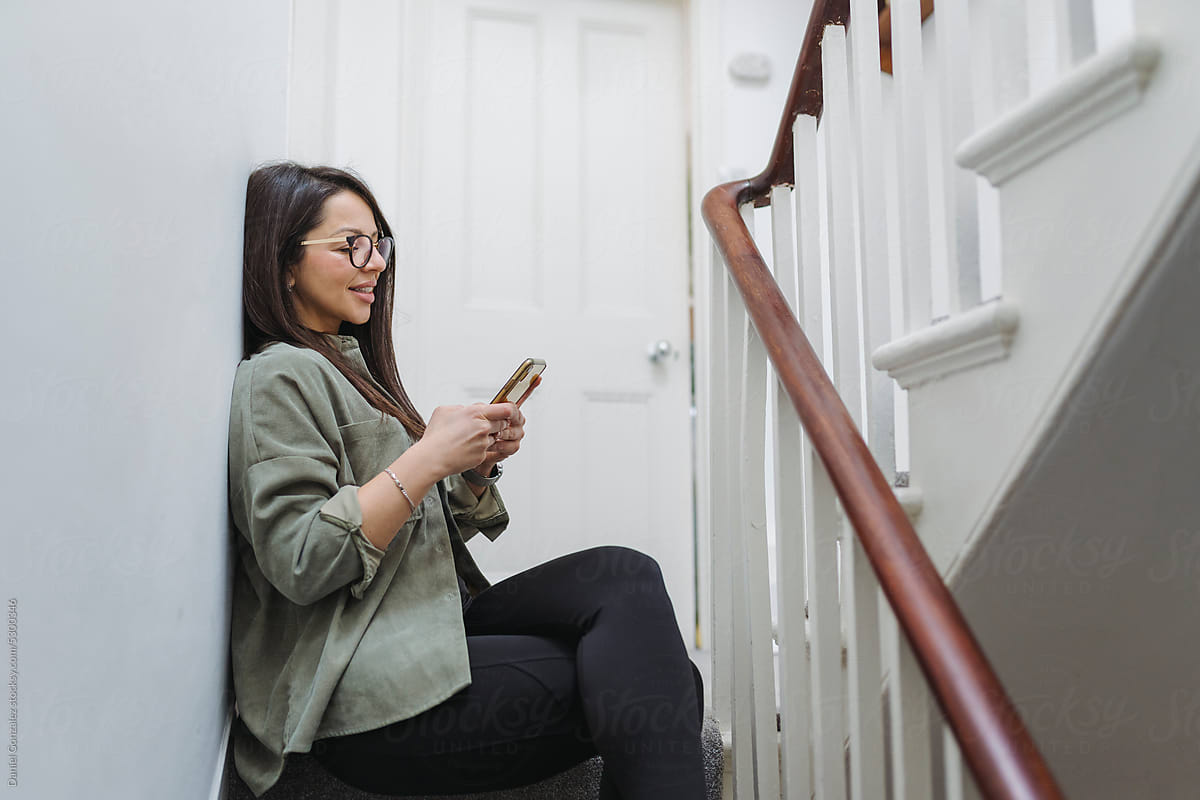 Woman with smartphone sitting on stairs