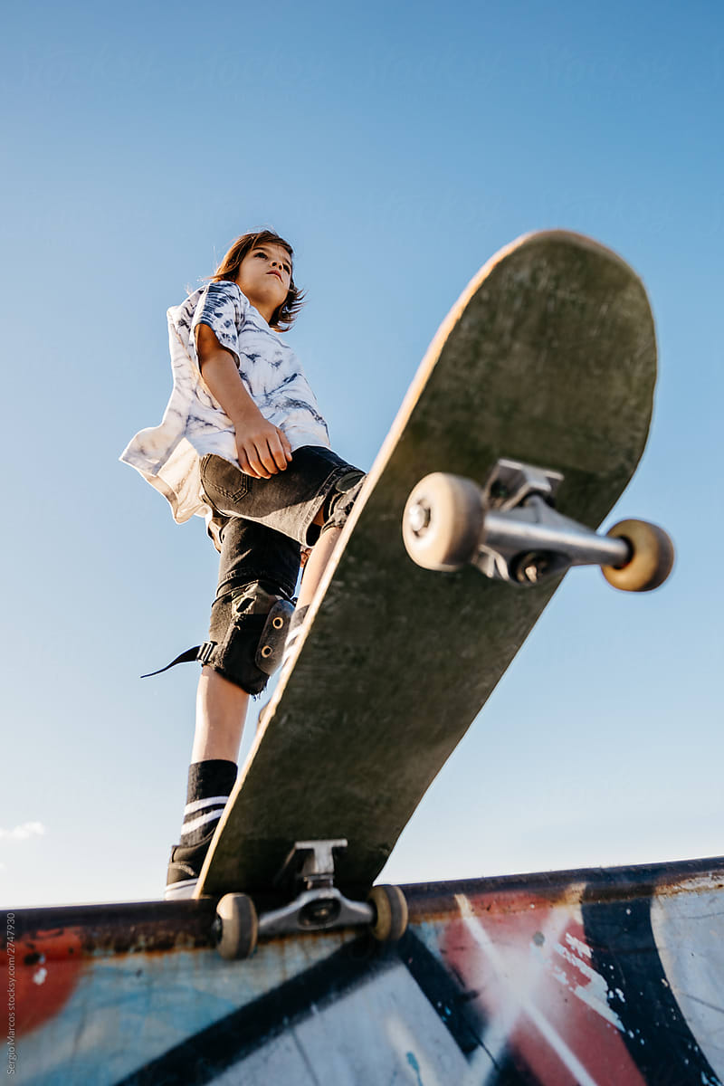 Kid with skateboard on ramp in skatepark