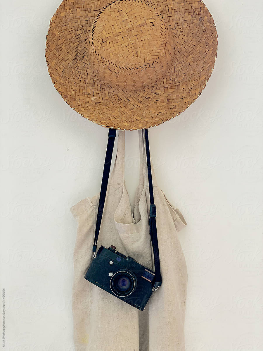 A straw hat, retro camera and a bag hang on a hanger