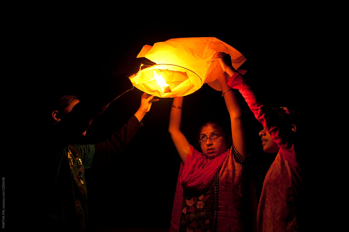Young woman and teenagers releasing sky lantern to the sky