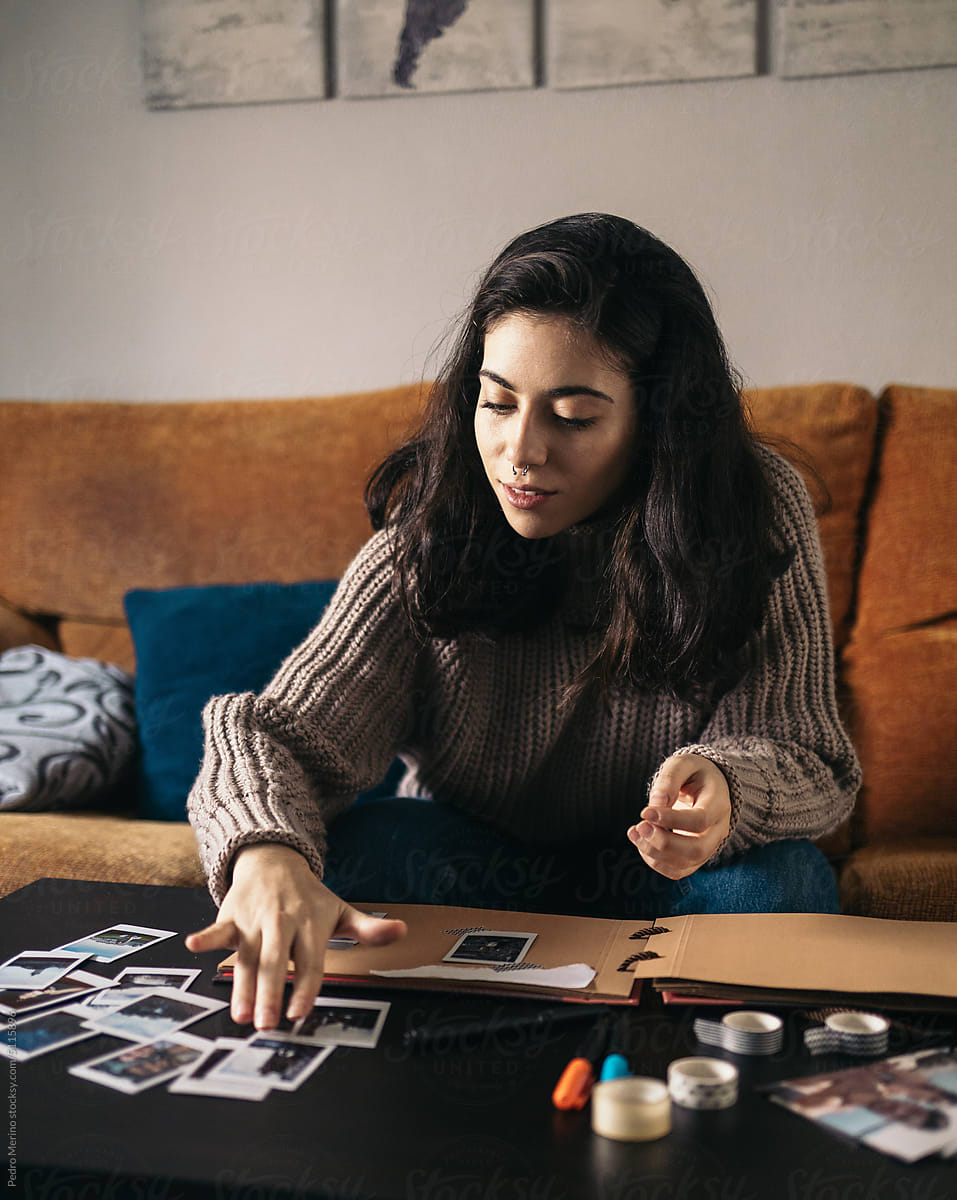 Young woman making an album with polaroid photos at home