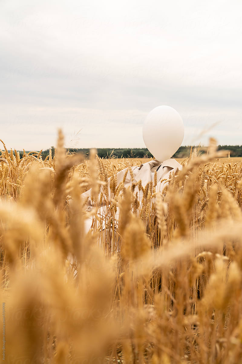 Beige trench coat laying at the wheat field with white balloon