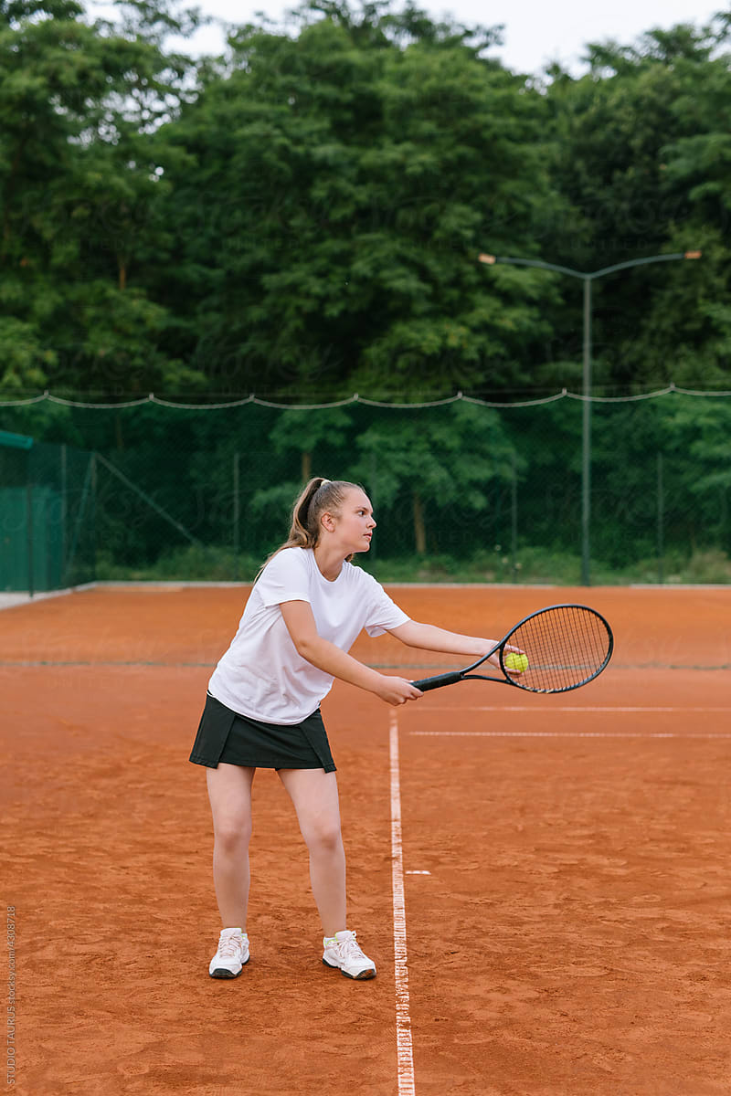 Young girl playing tennis on the tennis court