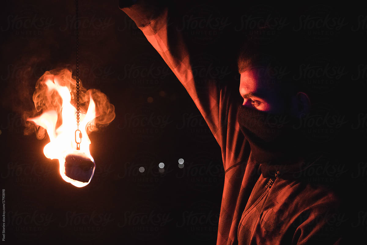 Fire dancer holding lit pois in front of his face