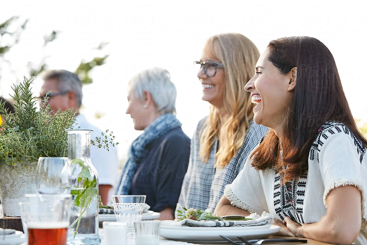 Woman laughing with friends at outdoor dinner