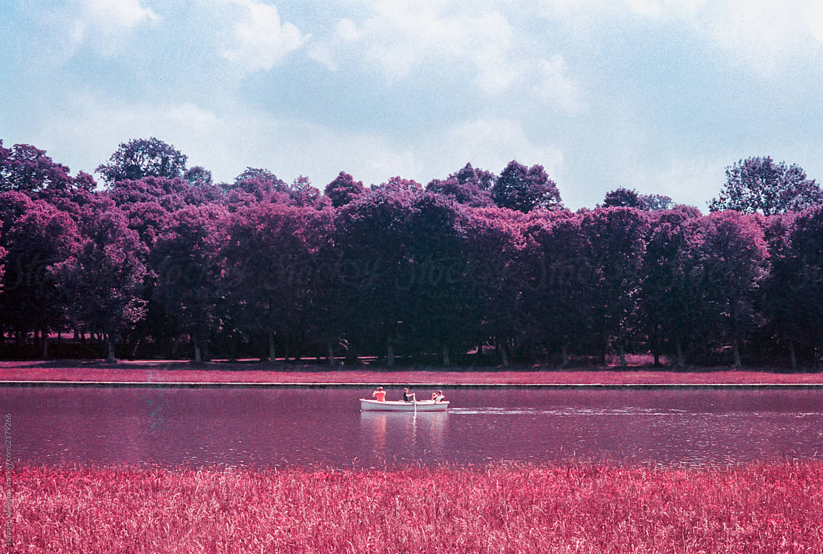 Family in rowboat in surreal magenta river