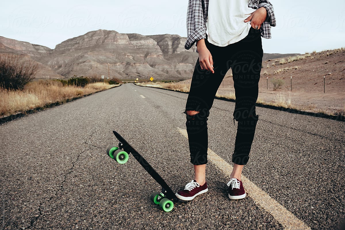 Hipster girl with skateboard on the road