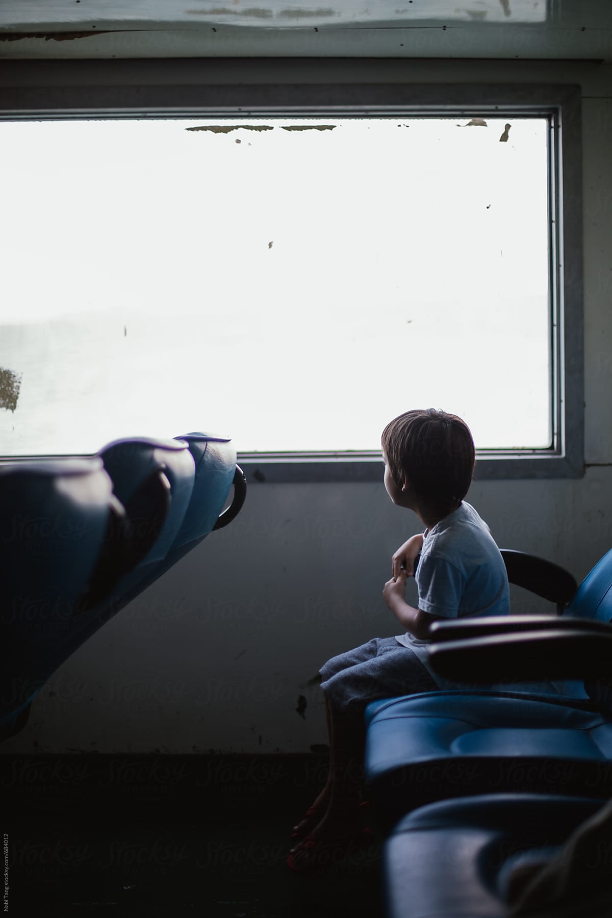 A boy chilling on the ferry looking outside of the window