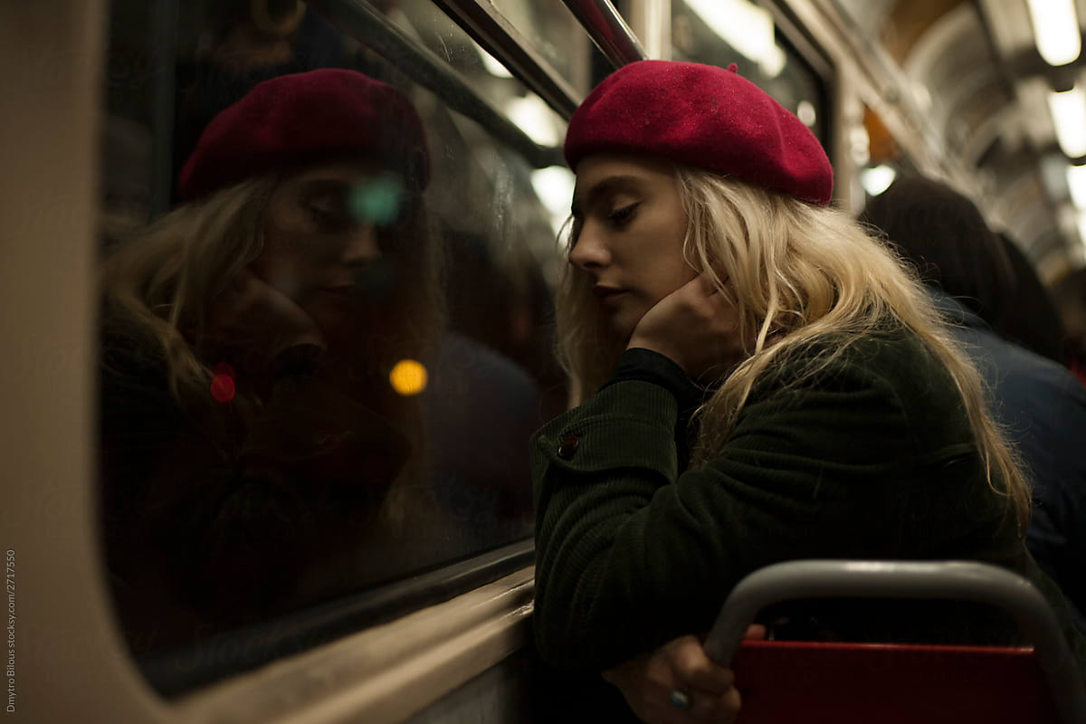 portrait of a sad girl in a red beret by the window in public transport