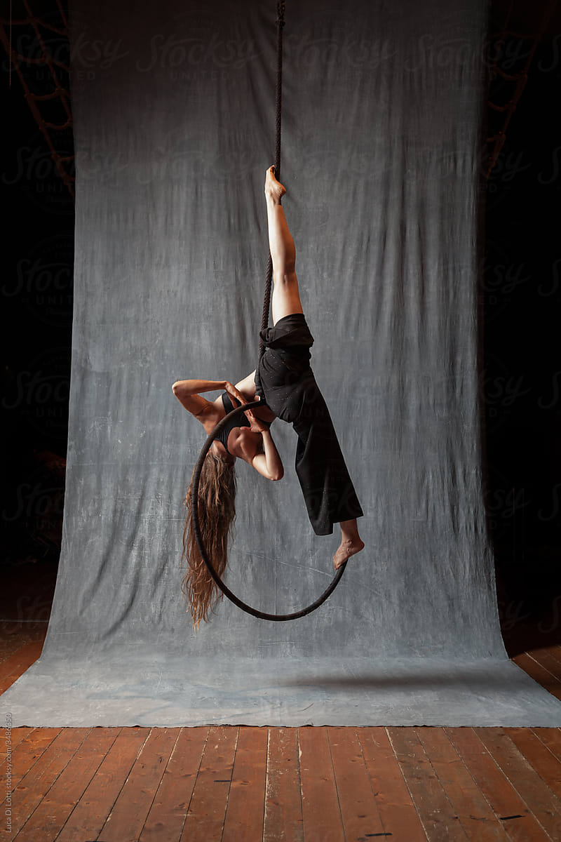 long-haired circus performer makes a split on a hoop
