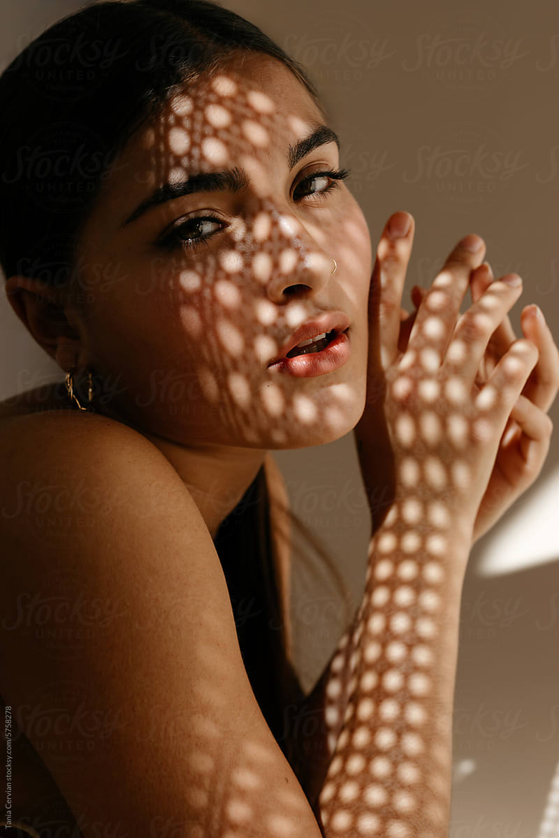 Crop woman in makeup sitting in room with shadows