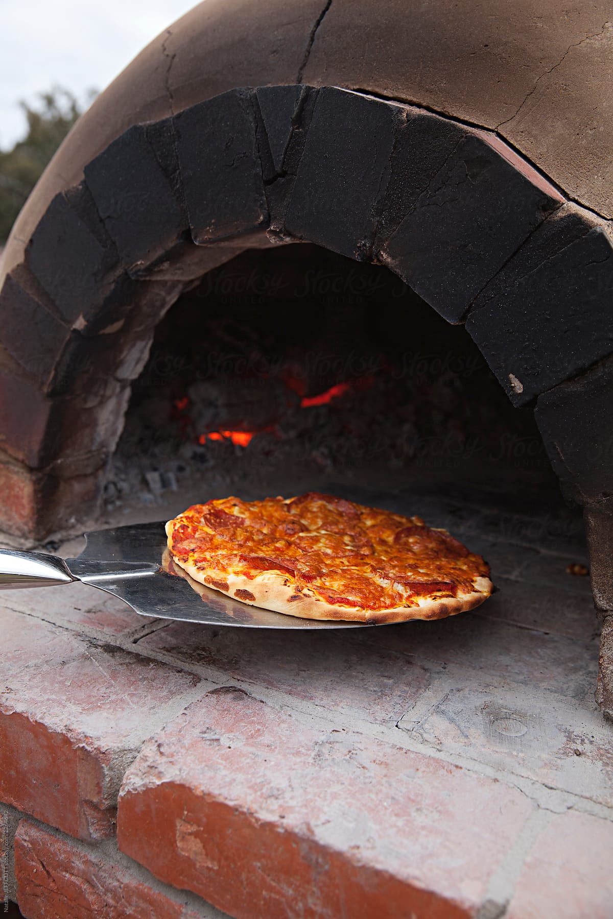 cooking home made pizza in wood fired oven