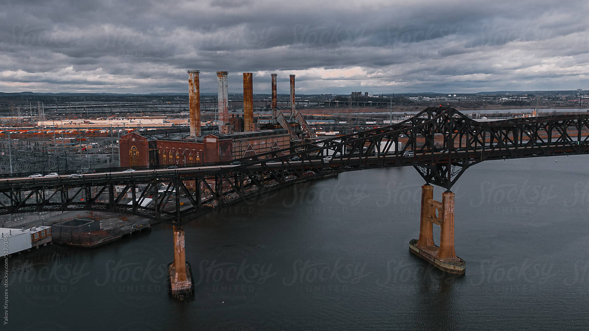 Old bridge across the river and forsaken factory on the shore