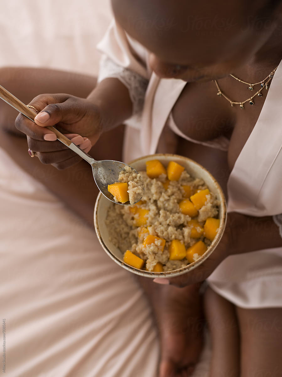 Black pregnant woman eating porridge with fruits
