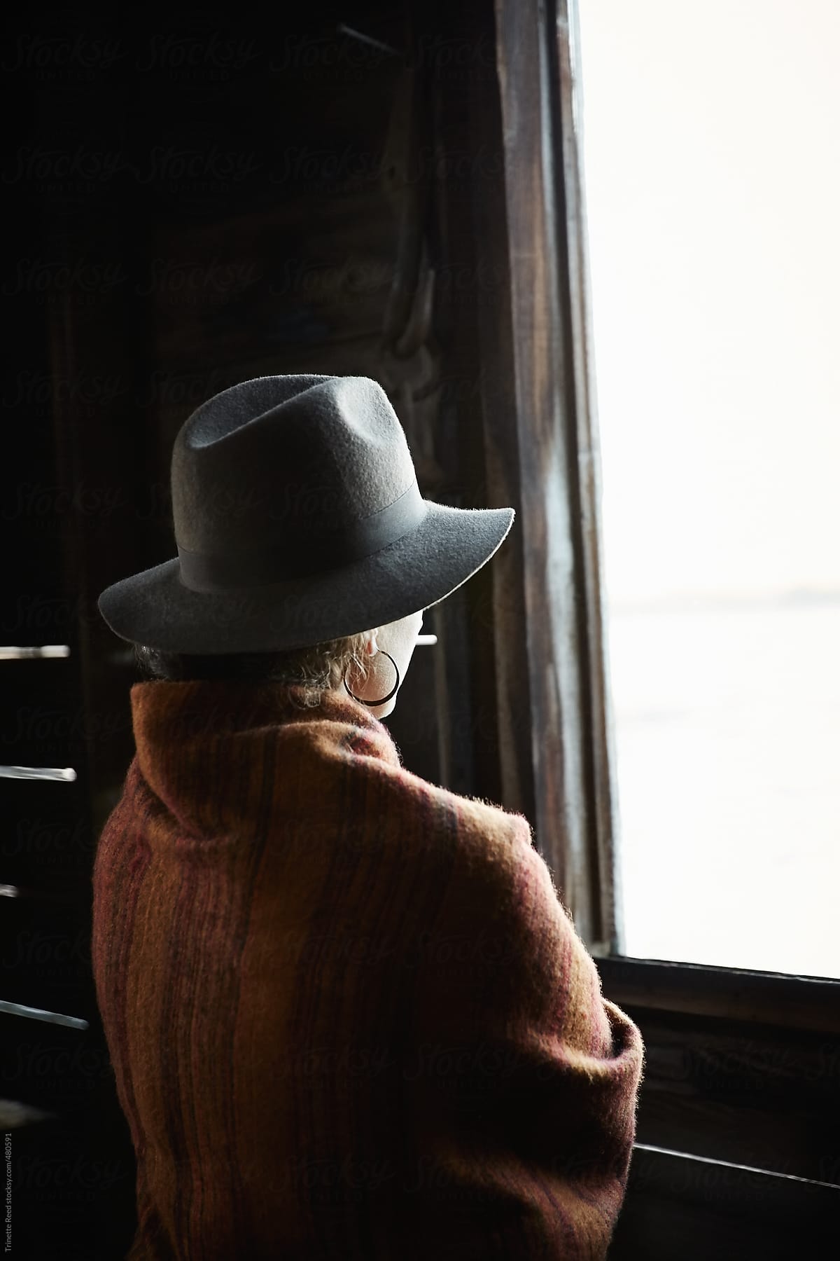 Woman looking out window with hat on