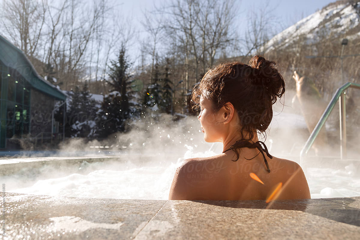 Young woman sitting in hot spring pool in winter