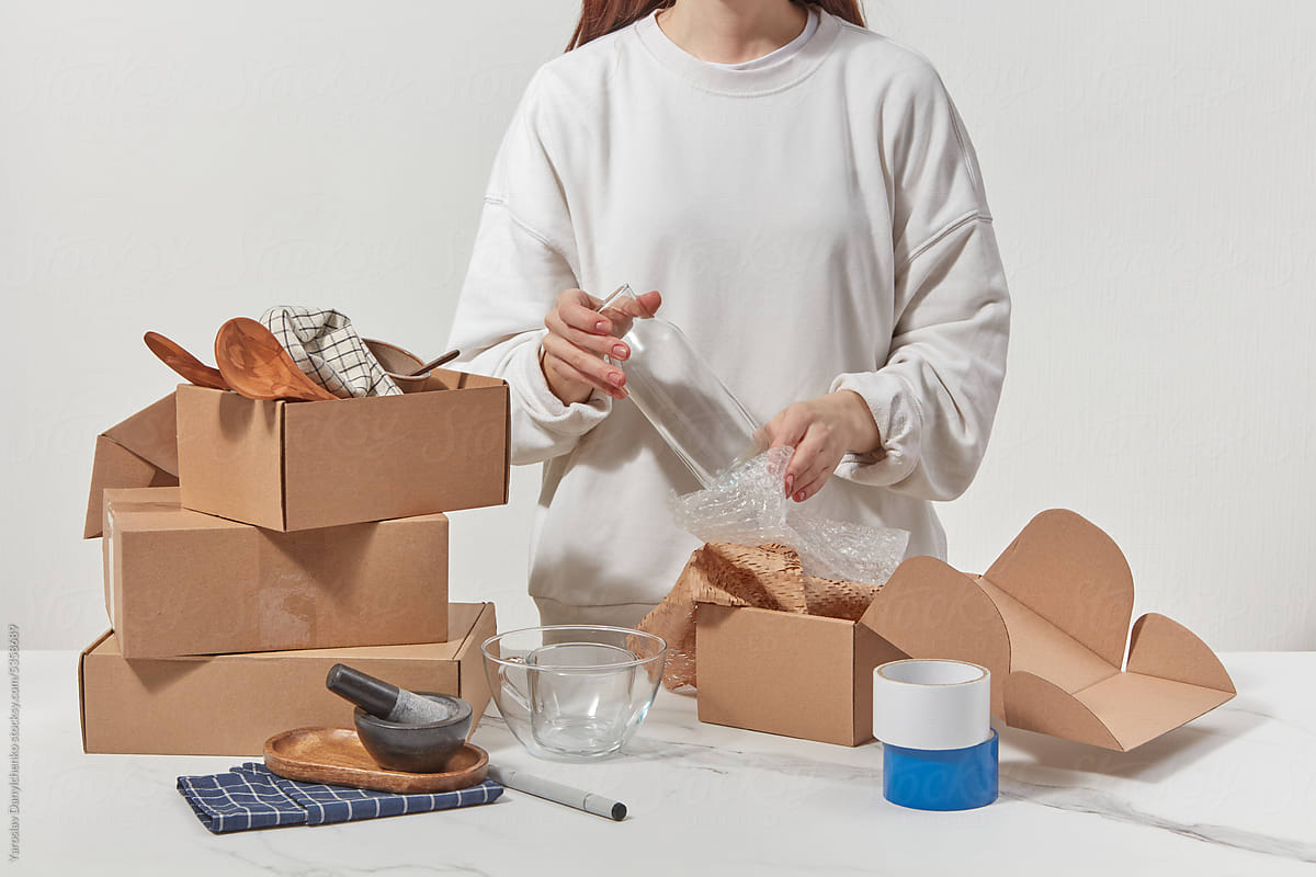 Woman wrapping glassware in packaging and putting in boxes.